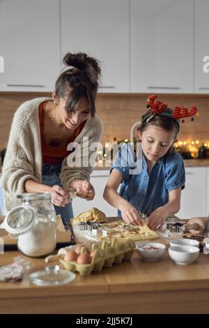 Une mère souriante avec sa fille qui fait des biscuits dans la cuisine Banque D'Images