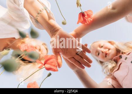 Filles avec mère empilant les mains sous le ciel bleu Banque D'Images