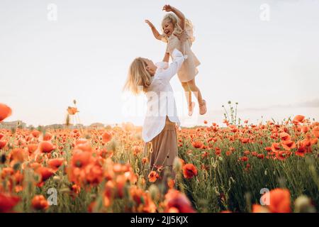 Une mère ludique qui lève sa fille dans l'air le jour du soleil Banque D'Images