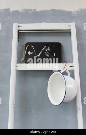 Pot de chambre suspendu sur l'échelle tenant l'affiche des toilettes sur le tableau noir Banque D'Images