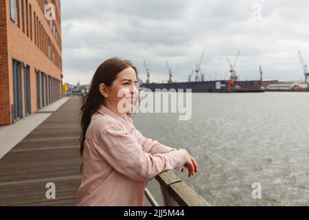 Bonne jeune femme debout près des balustrades au port de Hambourg Banque D'Images