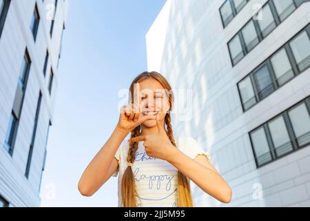 Bonne fille faisant le geste tictoc devant le bâtiment Banque D'Images