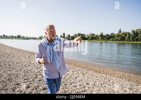 Homme senior qui fait des gestes et marche sur la rive Banque D'Images