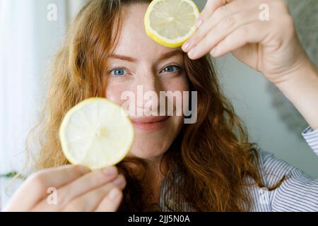 Femme souriante tenant des tranches de citron Banque D'Images