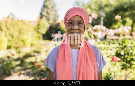 Femme âgée souriante avec foulard dans le parc Banque D'Images