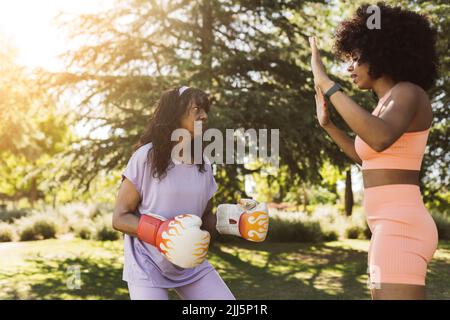 Femme âgée déterminée pratiquant la boxe avec sa fille dans le parc Banque D'Images