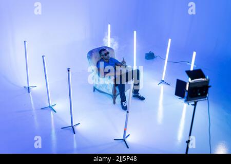 Chanteur assis sur une chaise avec équipement d'éclairage dans un studio de cinéma Banque D'Images