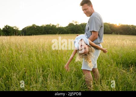 Un père souriant transportant sa fille s'amusant sur le terrain Banque D'Images