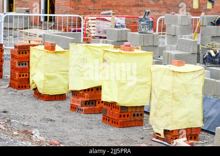 Briques rouges et blocs de béton livrés sur le chantier et placés à côté du lieu de travail prêt pour les briques Banque D'Images