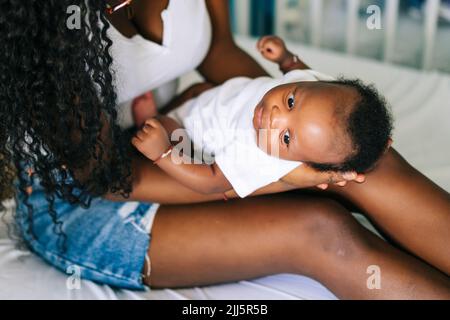 Mère avec bébé garçon sur les genoux à la maison Banque D'Images