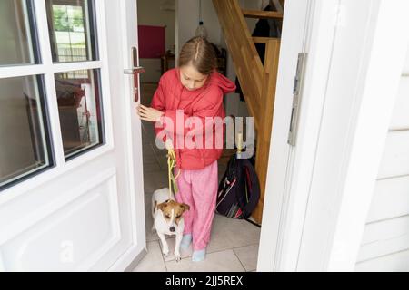 Fille avec chien à l'entrée de la maison Banque D'Images