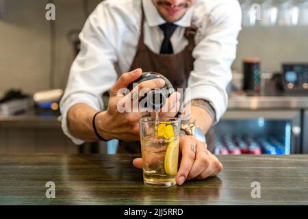 Le barman verse la boisson dans le verre au comptoir du bar Banque D'Images