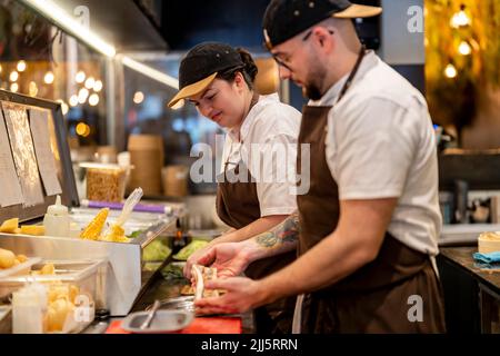 Chef cuisinier préparant la nourriture par un collègue dans la cuisine du restaurant Banque D'Images