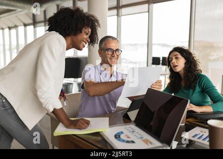 Des collègues souriants discutent à la réception au bureau Banque D'Images