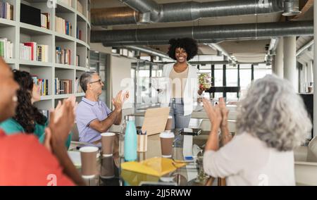 Des collègues d'affaires heureux applaudissent pour femme d'affaires avec des boîtes à lunch dans le bureau Banque D'Images