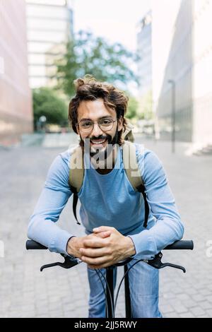 Homme barbu souriant pendu vélo en ville Banque D'Images