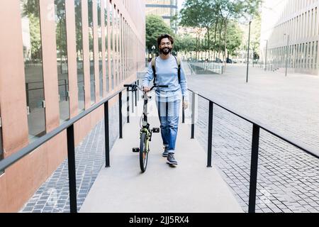 Homme avec vélo marchant sur le trottoir dans la ville Banque D'Images