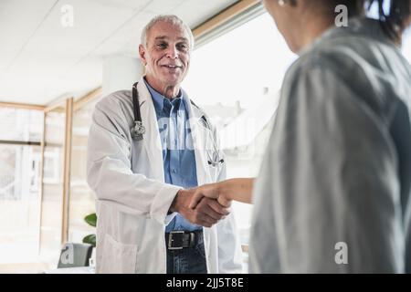 Un médecin heureux se secouant la main avec le patient en clinique médicale Banque D'Images