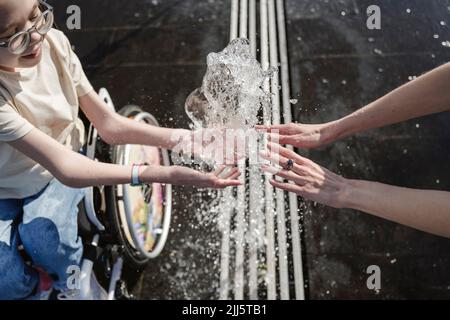 Mère et fille jouant avec une fontaine au parc Banque D'Images