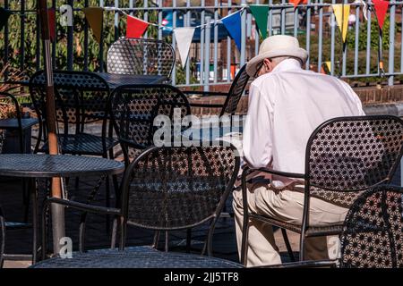 Dorking Surrey Hills Royaume-Uni, 10 juillet 2022, senior Homme assis seul dans le café à l'extérieur terrasse détente et lecture Banque D'Images