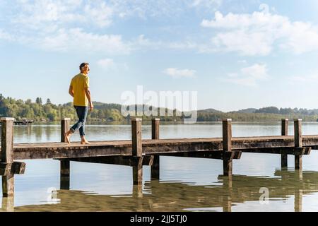 Homme marchant sur la jetée au lac Banque D'Images