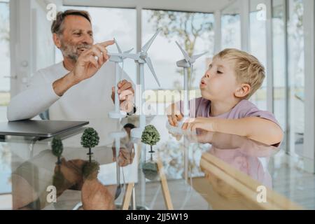 Père et fils heureux jouant avec le modèle d'éolienne Banque D'Images