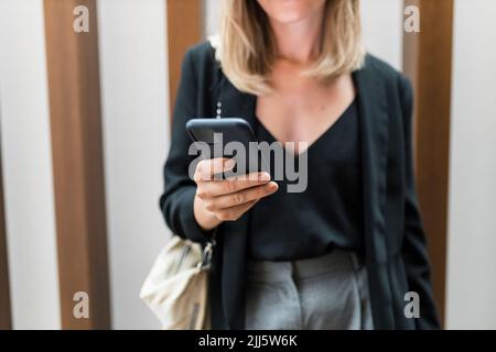 Mains d'une femme d'affaires utilisant un smartphone dans l'hôtel Banque D'Images