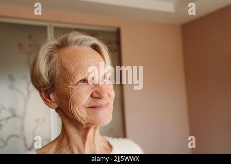 Femme âgée souriante avec de courts cheveux blancs à la maison Banque D'Images