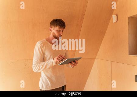 Homme qui a configuré un appareil intelligent avec une tablette numérique dans la maison écologique Banque D'Images