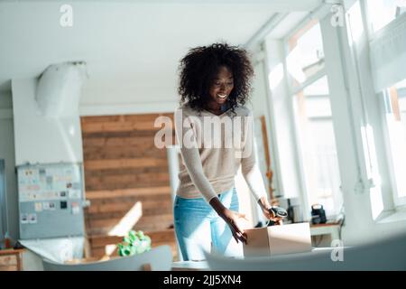 Femme d'affaires souriante tenant une boîte et un scanner Banque D'Images