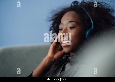 Une jeune femme souriante écoute de la musique avec un casque sans fil Banque D'Images
