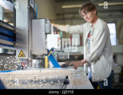 Homme mature avec machine CNC travaillant en usine Banque D'Images