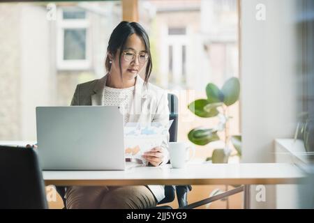 Femme d'affaires avec des documents assis au bureau Banque D'Images