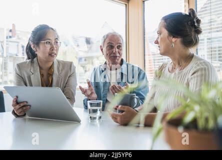 Des collègues souriants discutent de travail au bureau Banque D'Images