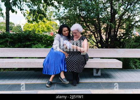 La mère lit la lettre avec sa fille assise sur le banc au parc Banque D'Images