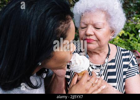 Mère partageant de la crème glacée avec sa fille dans le parc Banque D'Images