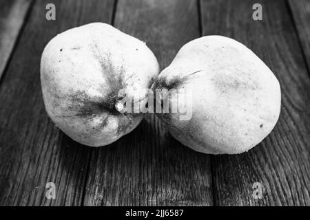 Coings isolés. Deux coings jaune sur une planche de bois. Banque D'Images