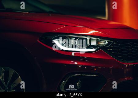 Magnifique tipo de fiat rouge garée dans un garage sombre avec des lumières avant et arrière éblouissantes. Banque D'Images