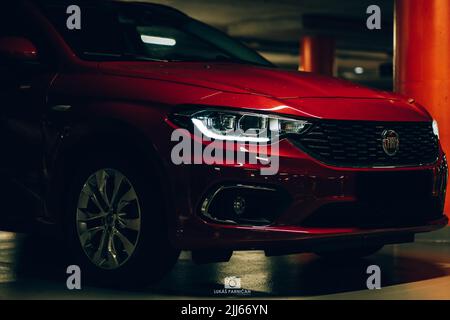 Magnifique tipo de fiat rouge garée dans un garage sombre avec des lumières avant et arrière éblouissantes. Banque D'Images