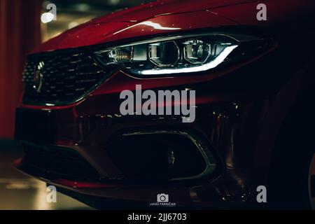 Magnifique tipo de fiat rouge garée dans un garage sombre avec des lumières avant et arrière éblouissantes. Banque D'Images