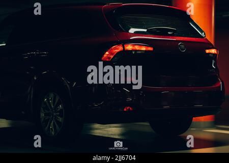 Magnifique tipo de fiat rouge garée dans un garage sombre avec des lumières avant et arrière éblouissantes. Banque D'Images