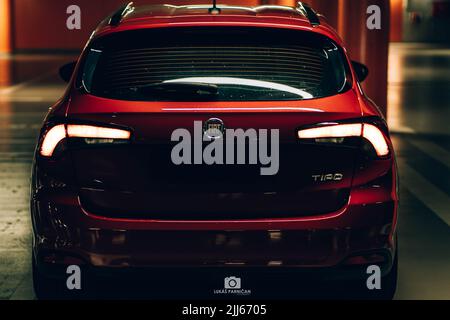 Magnifique tipo de fiat rouge garée dans un garage sombre avec des lumières avant et arrière éblouissantes. Banque D'Images