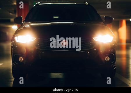 Magnifique tipo de fiat rouge garée dans un garage sombre avec des lumières avant et arrière éblouissantes. Banque D'Images