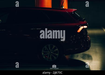 Magnifique tipo de fiat rouge garée dans un garage sombre avec des lumières avant et arrière éblouissantes. Banque D'Images