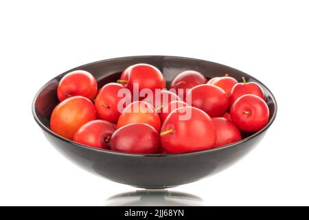 Plusieurs prunes mûres de cerise juteuse dans une plaque en céramique noire, en gros plan, isolées sur un fond blanc. Banque D'Images