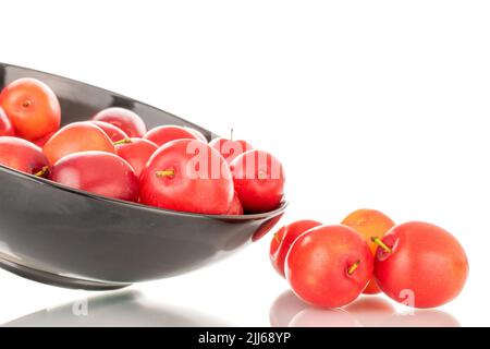 Plusieurs prunes mûres de cerise juteuse dans une plaque en céramique noire, en gros plan, isolées sur un fond blanc. Banque D'Images