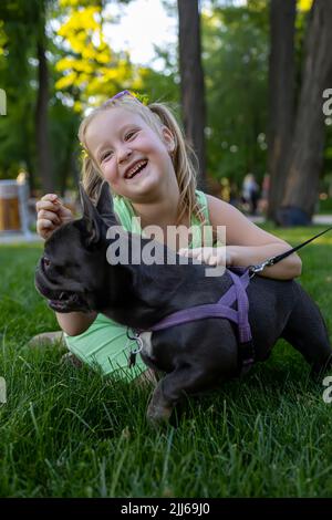 une petite fille gaie embrassait un chien de boudogue français et riait en miette Banque D'Images