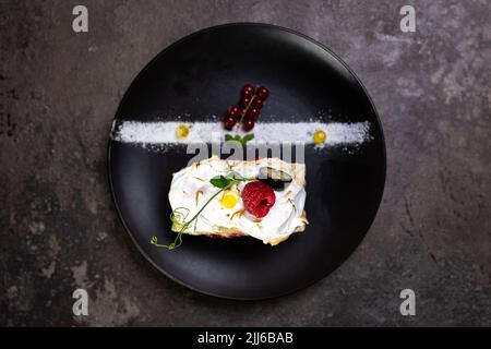rouleau tendre avec framboises fraîches sur une assiette noire. service dans un restaurant vue sur le dessus. Banque D'Images