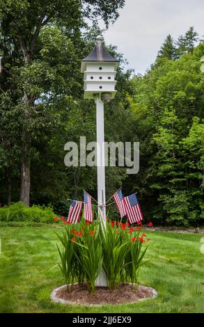 Birdhouse sur un poteau dans une arrière-cour avec des drapeaux et des fleurs américains, Grafton, Vermont, VT États-Unis US New England Birdhouses Banque D'Images