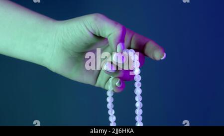 Femme priant et tenant des perles de mala à la main pour les comptes pendant les méditations de mantra. Lady sur fond bleu. Spiritualité, religion, concept de Dieu. Banque D'Images